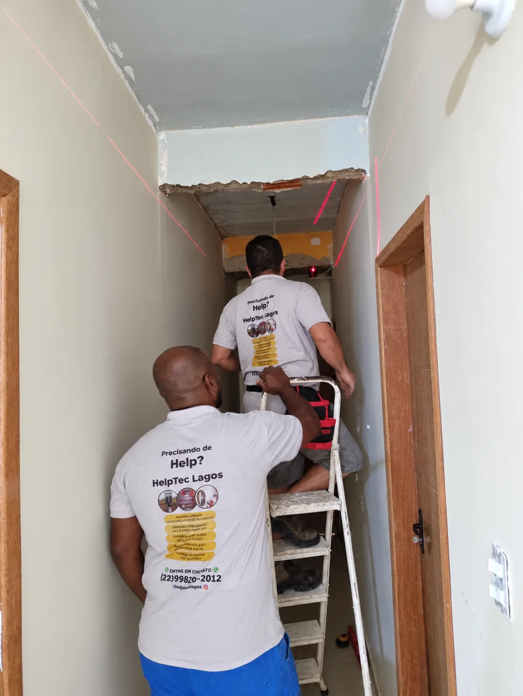 Equipe da Helptec Lagos trabalhando em um corredor com escada e nivelamento a laser